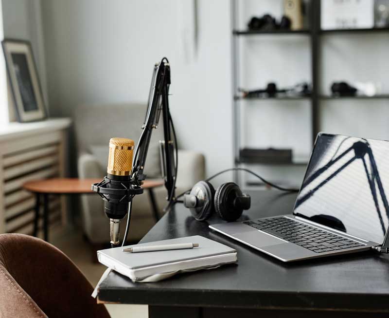 closeup of laptop, notebook, headphones, and mic