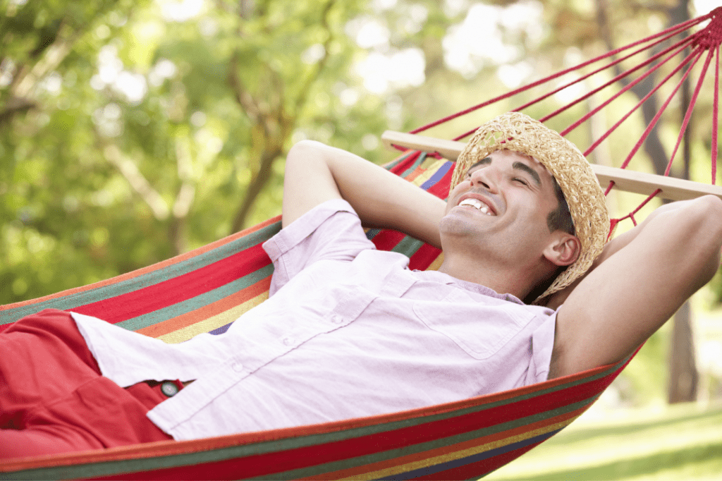 Man wearing hat in hammock smiling