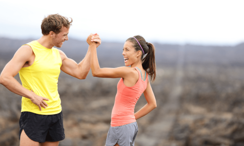 A man and woman enthusiastically high-five each other during their exciting podcast session.